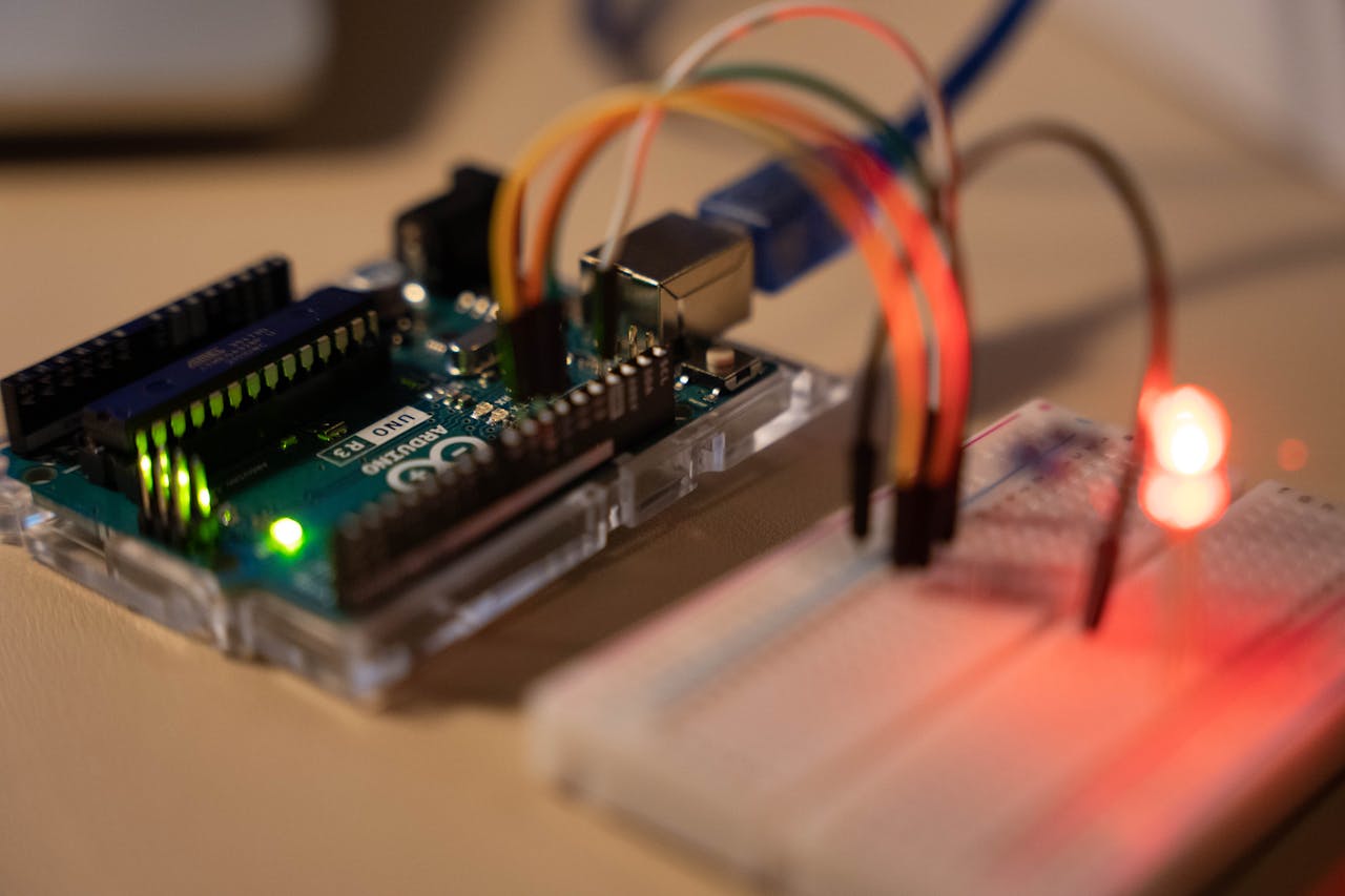 Close-up of Arduino microcontroller connected to a breadboard with a glowing LED.